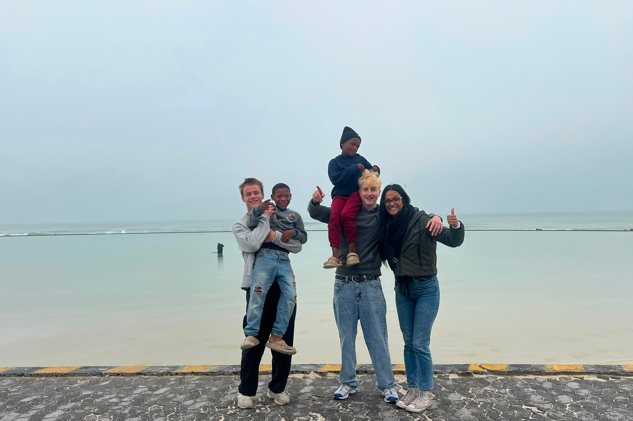 Three volunteers on the beach with a child on their shoulders