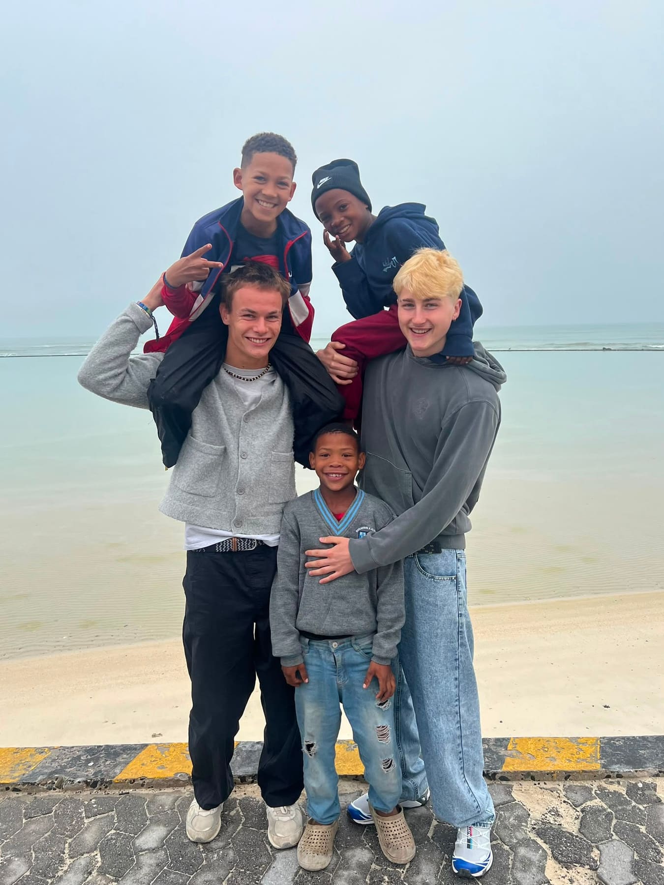 Volunteers carrying children on their shoulders at the shoreline