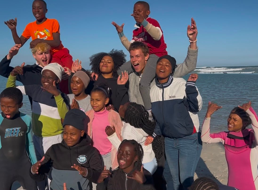 A crowd of children and volunteers cheering on the beach